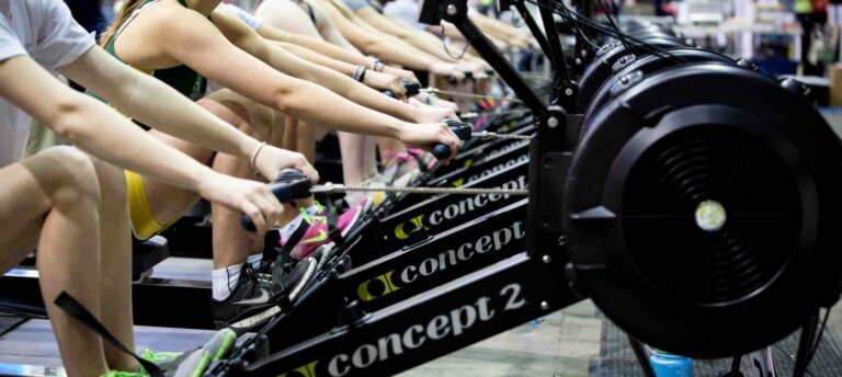 A lineup of Concept 2 Rowing machines with rowers holding the handles.